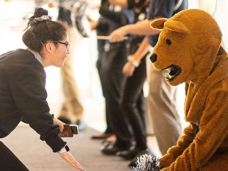 Student interacting with Nittany Lion mascot.